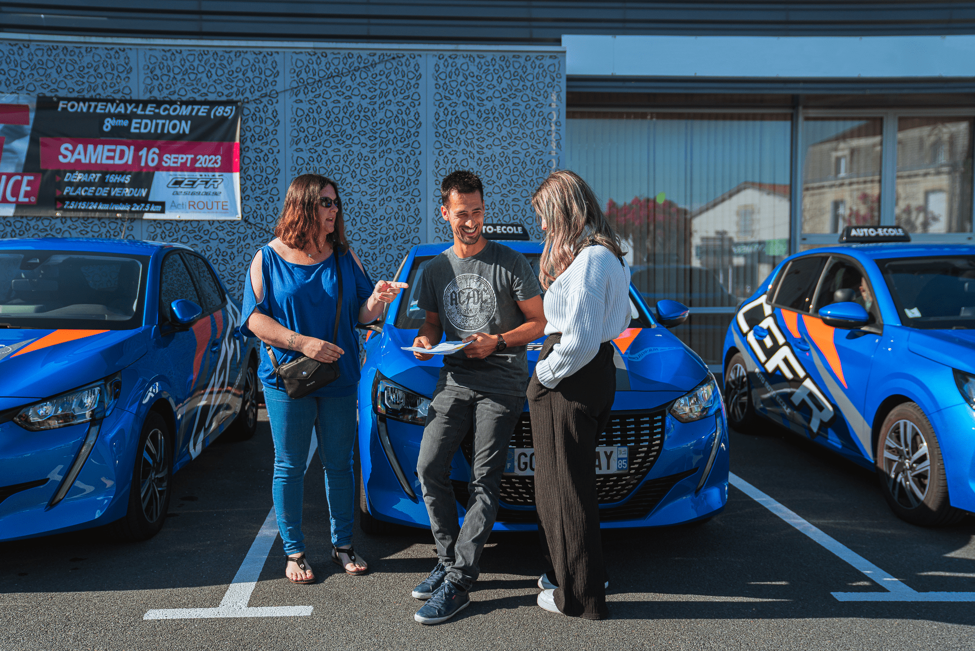 Moniteur accompagner de 2 élèves devant le parc automobile
